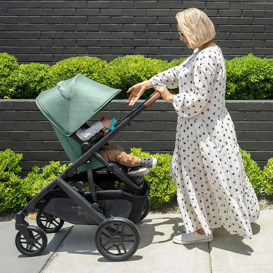 A child is pushed by a smiling woman on a sunny day in the included Toddler Seat with the help of an extended Vista canopy that shields the child from harmful UV rays