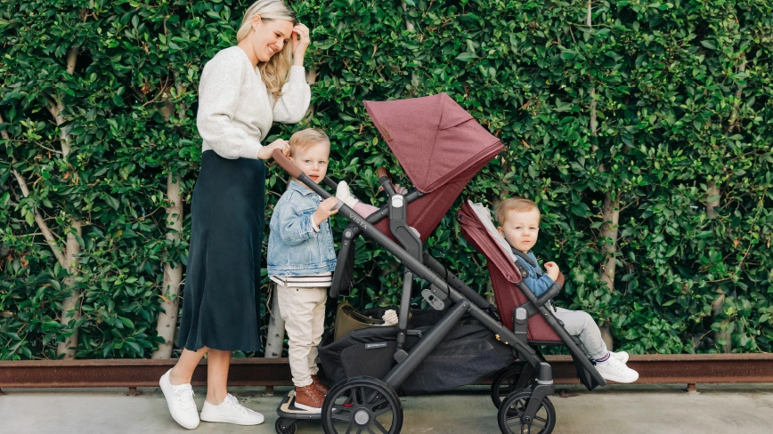 A child sitting in the Vista's included Toddler Seat is comfortably pushed by a smiling man and woman who use the stroller's adjustable handlebar with extra-grip
