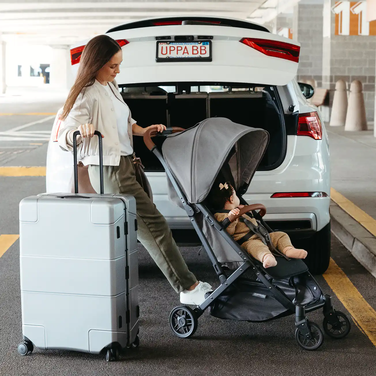 A woman brakes her Minu V2 stroller outside of an airport, ready to load the travel stroller into a car due to its compact one-handed fold