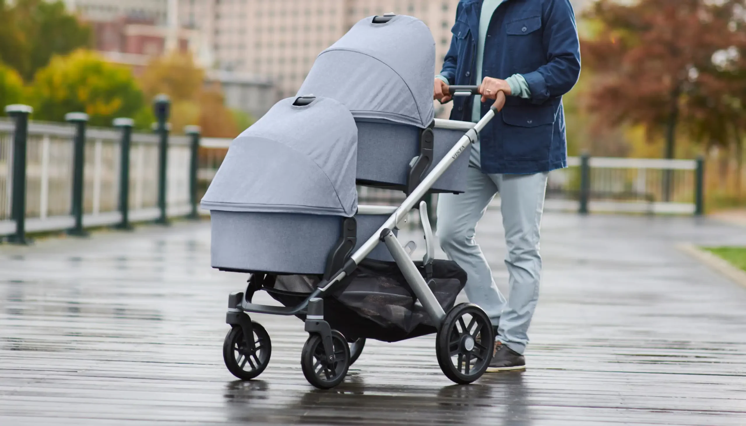 Parent pushes two children in Bassinets attached Vista Stroller