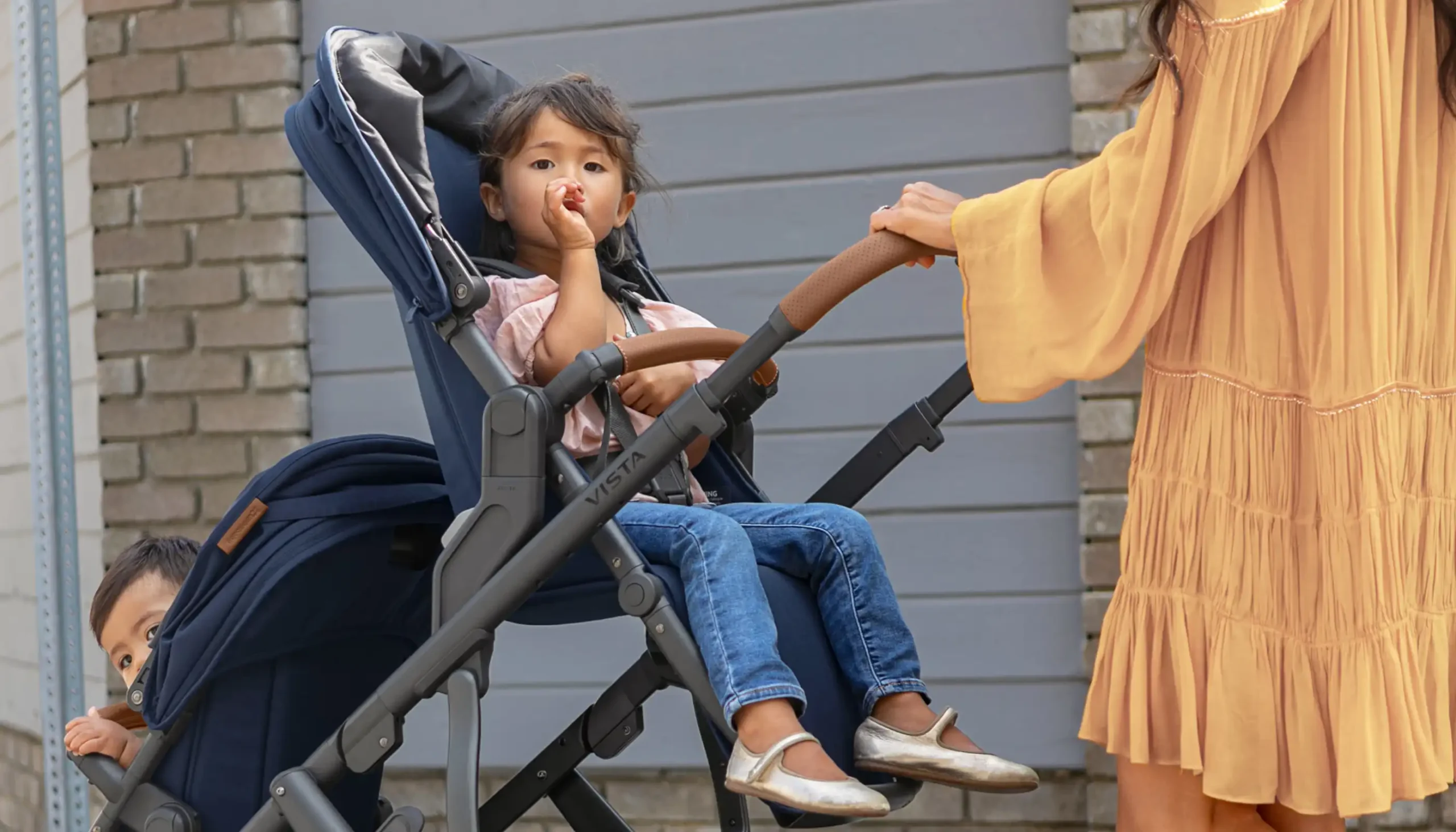 Parent pushing children in Vista Stroller with Brown Leather Handle Bar cover