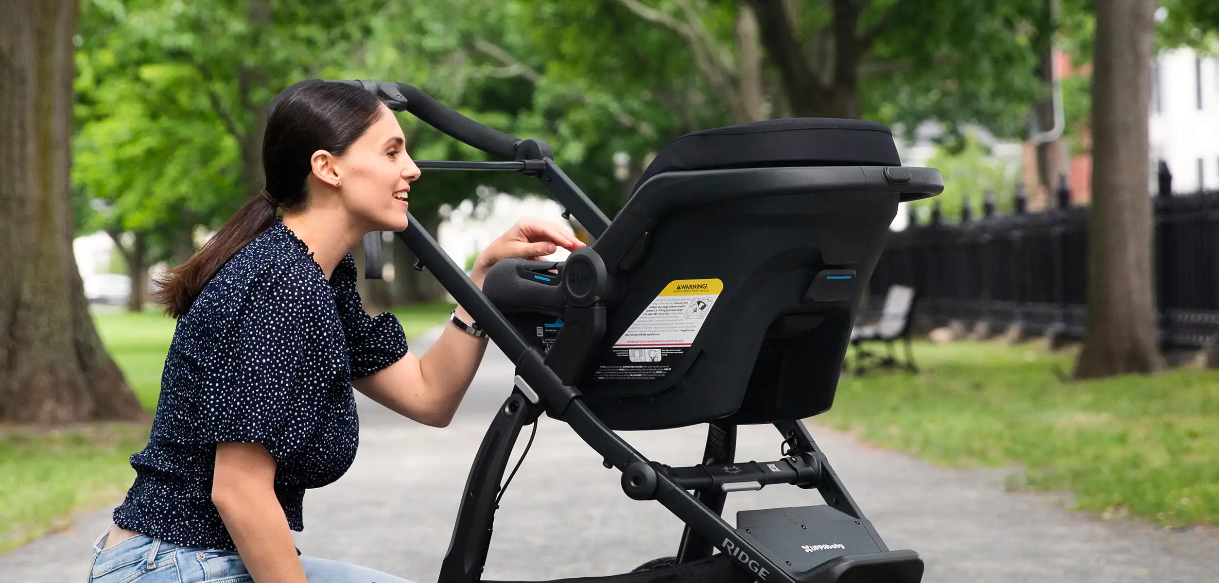 A woman smiles at her child in a Mesa Max car seat which, when attached to the Ridge using convinient adapters, turns the jogging stroller into an option for on-the-go infant usage