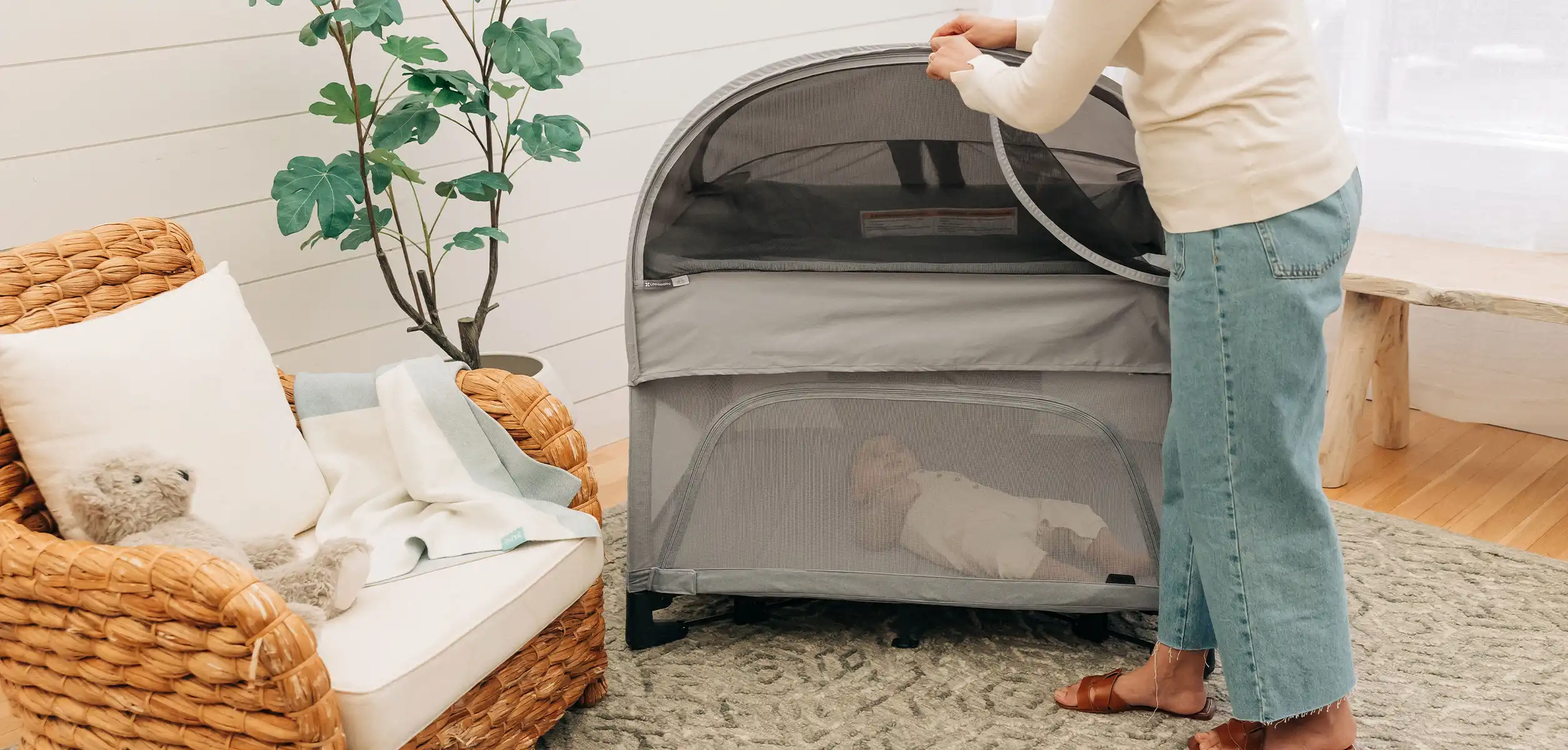 A woman easily attaches the Remi Canopy accessory to her Remi inside to darken the room for her infant