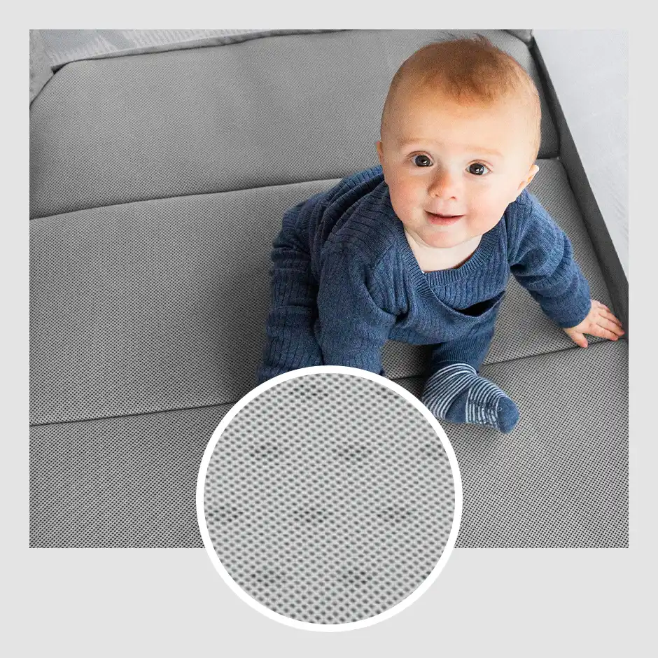 A smiling infant sits themselves up on Remi's triple layer mattress, that is shown to be made from air mesh for improved breathability