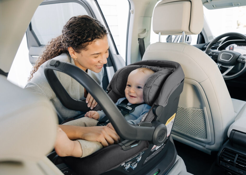 A mother securing her little one into an UPPAbaby Mesa Max Infant Car Seat.