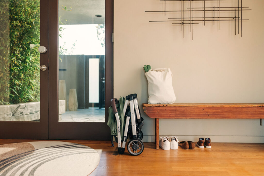 An entryway featuring a folded UPPAbaby Minu V2 | Emelia | Sage Green Mélange | Silver Frame | Chestnut Leather.