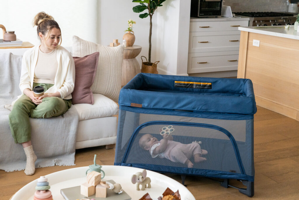 A mother with her child in an UPPAbaby Remi Playard in a family living room—Noa—Navy.