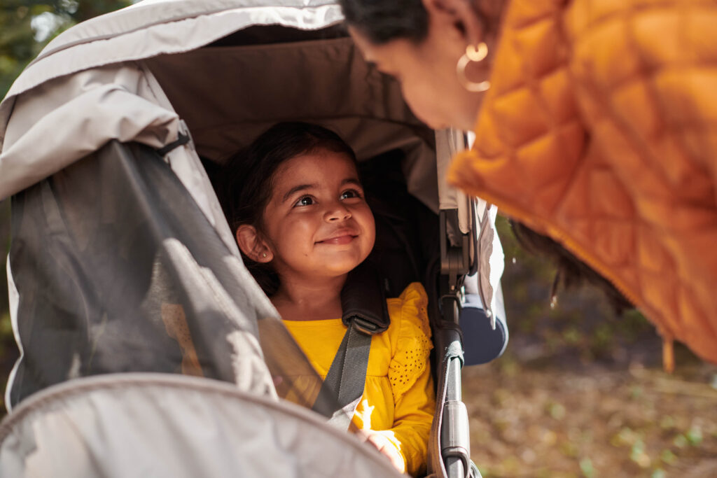 A mother looking at her daughter in a Ridge Stroller with an attached Sun and Bug Shield.