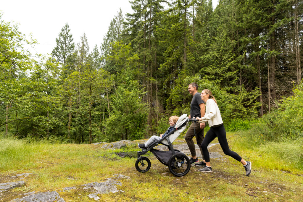 A mother and father adventuring with their little one in an UPPAbaby Ridge Stroller.