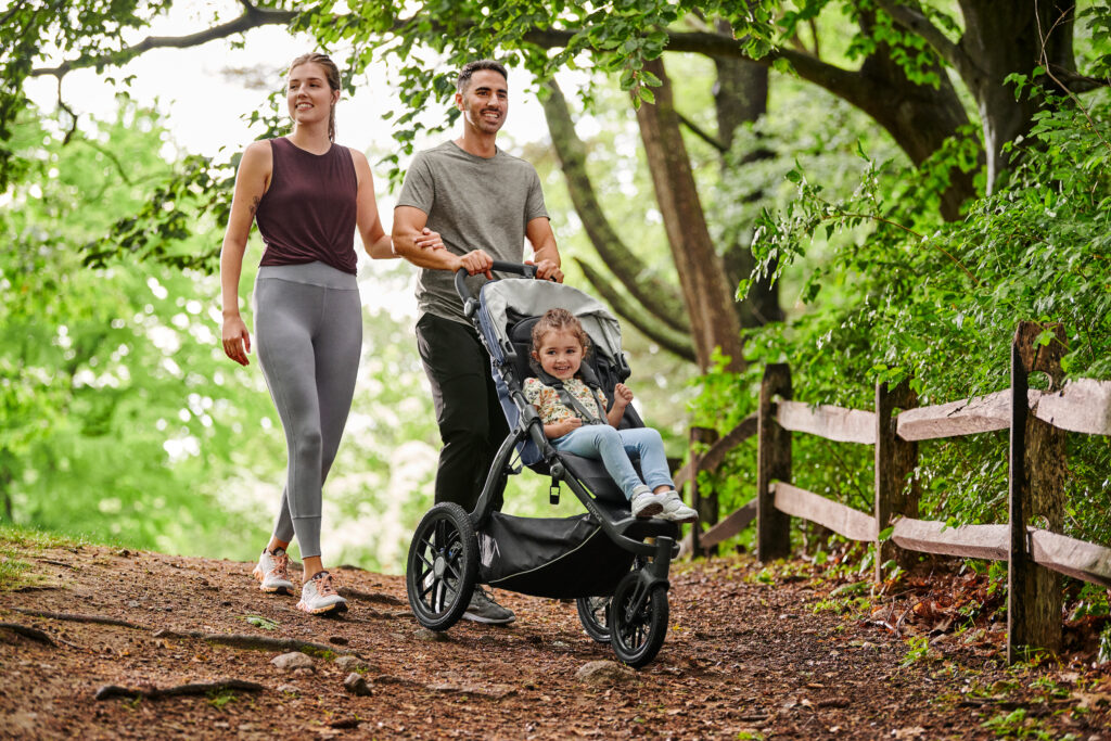 A mother and father adventuring with their little one in an UPPAbaby Ridge Stroller.