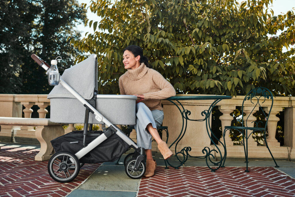 A mother looking in on her child in their UPPAbaby Cruz V2 with Bassinet