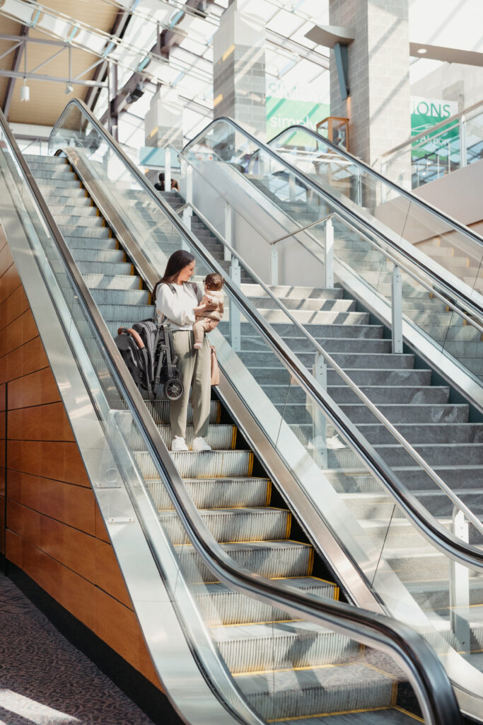 A parent navigating an escalator with ease using the UPPAbaby Minu V2 stroller, perfect for travel and city life