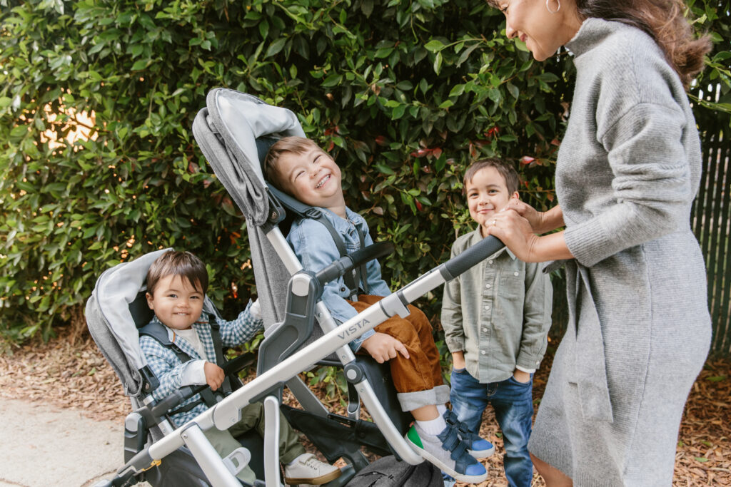 Joyful family moment with children interacting around an UPPAbaby Vista V2 stroller, demonstrating the stroller's versatility and capacity for sibling bonding