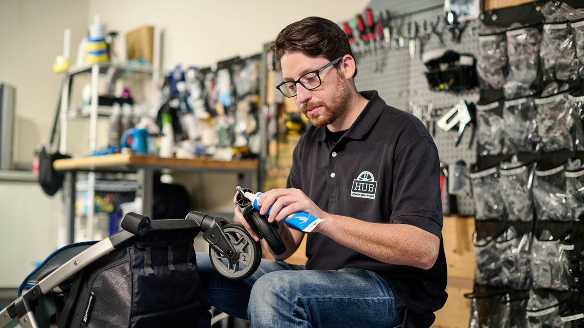 A Hub Service Center employee lubricating the wheel attachments of a Minu V2 stroller so that the stroller can be used safely and efficiently