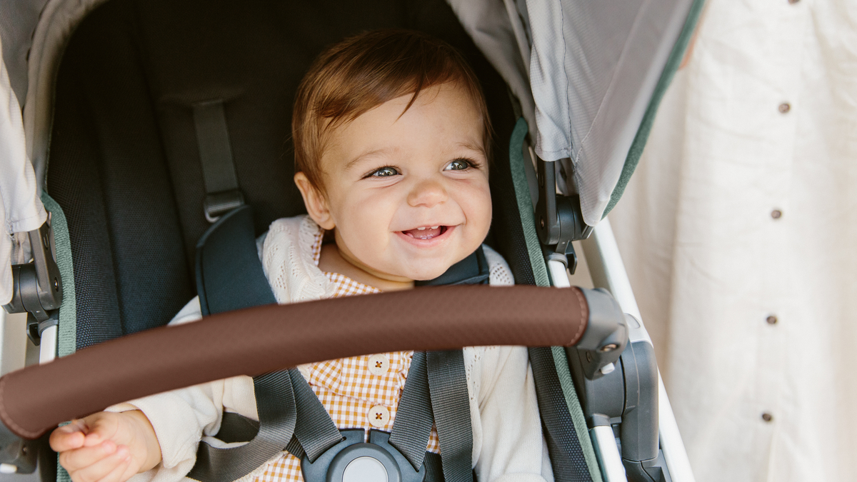 Happy baby enjoying a ride in the UPPAbaby VISTA stroller in Emmett green, showcasing the comfortable seat and robust design