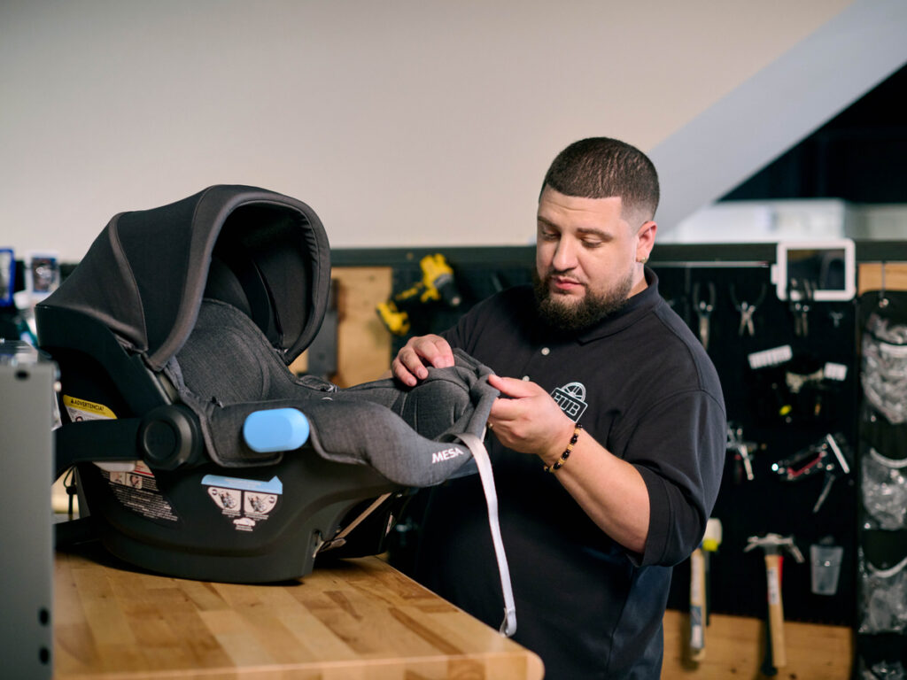 UPPAbaby Hub service technician attentively performing maintenance on a Mesa Car Seat, ensuring top-quality performance for customer satisfaction.