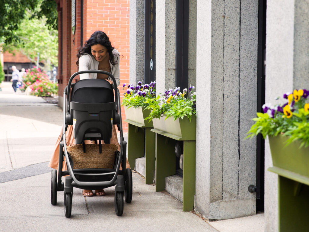 A woman strolls with her child in a Mesa V2 attached directly to a Vista V2 travel system, utilizing the Vista's all wheel suspension and 30lb basket