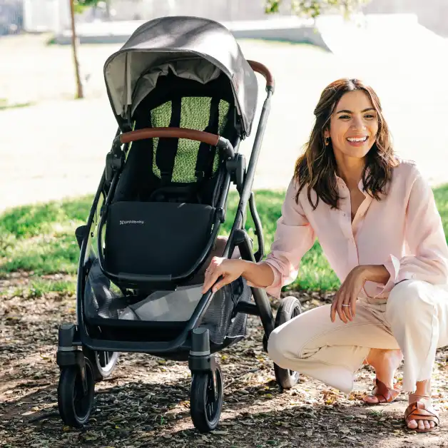 Mom kneeling beside Vista V3 toddler seat with mesh backing