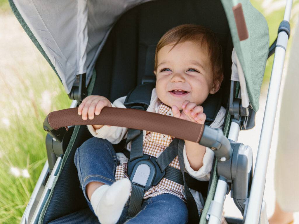 Baby smiles as they are securely buckled into the Vista V2 stroller. 