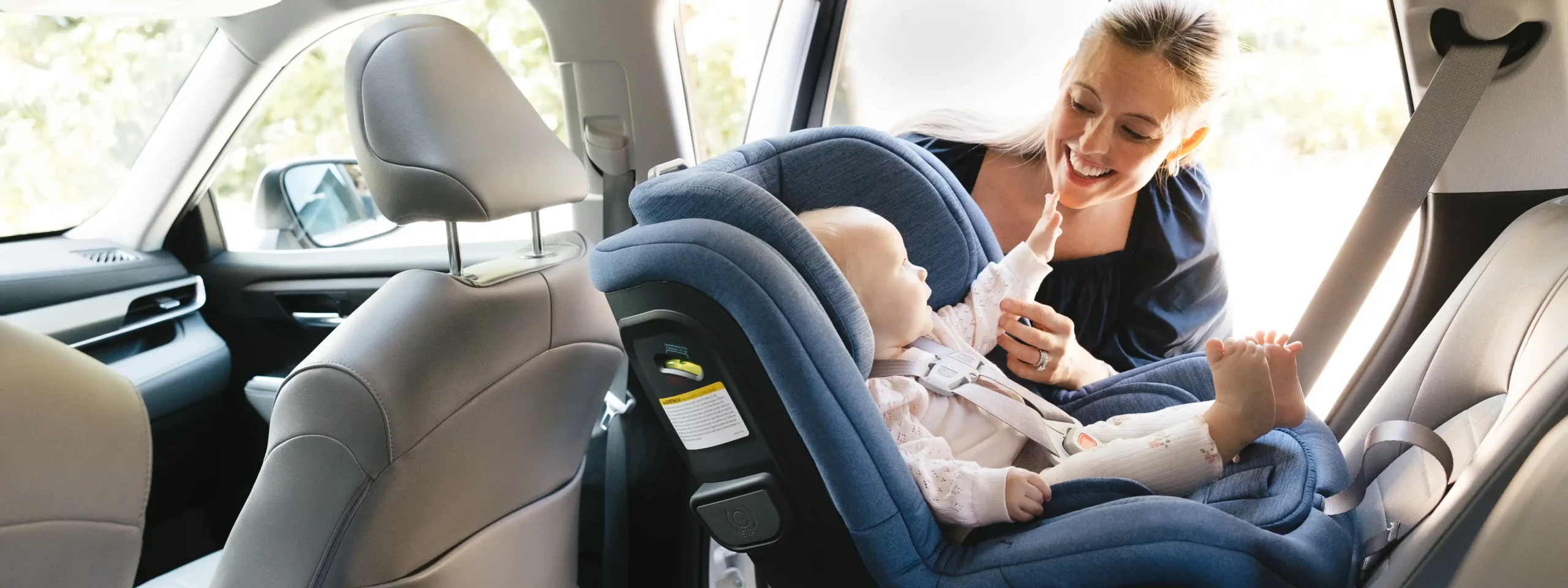 A parent engages with their child who is securely fastened in a rear-facing car seat